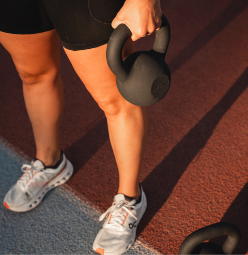 Zbliżenie na kobiece dłonie trzymające kettla podczas treningu na bieżni.